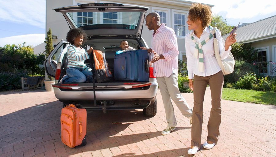 Black family loading car with suitcases